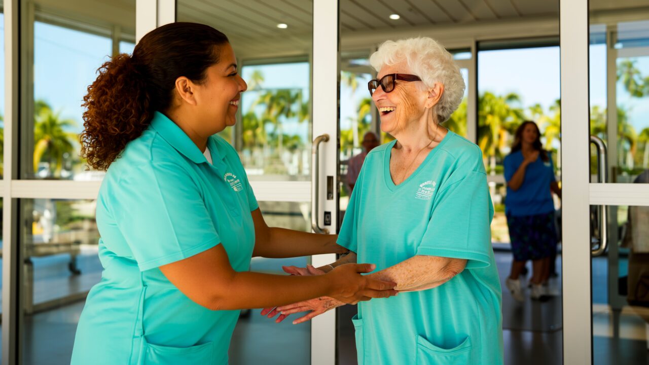 Staff member warmly welcoming a senior woman at the entrance of an adult day center in Broward County