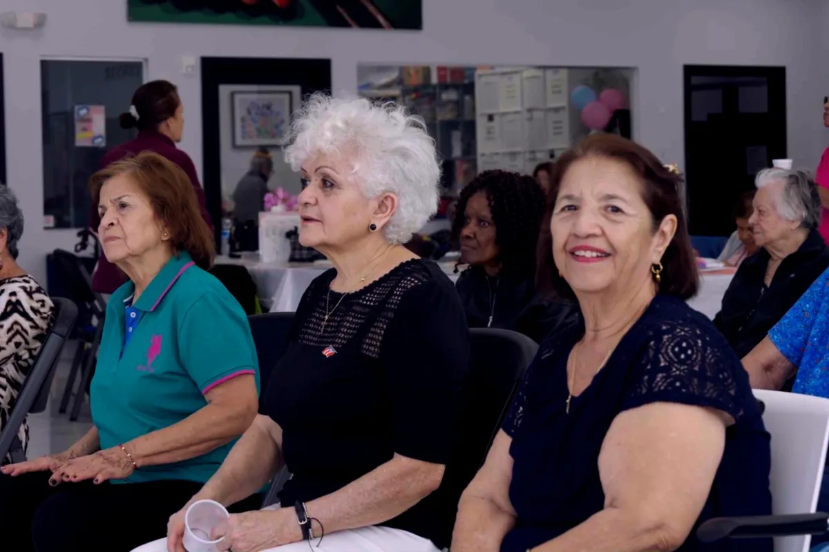 Several older women sit together and smile during an activity at the center